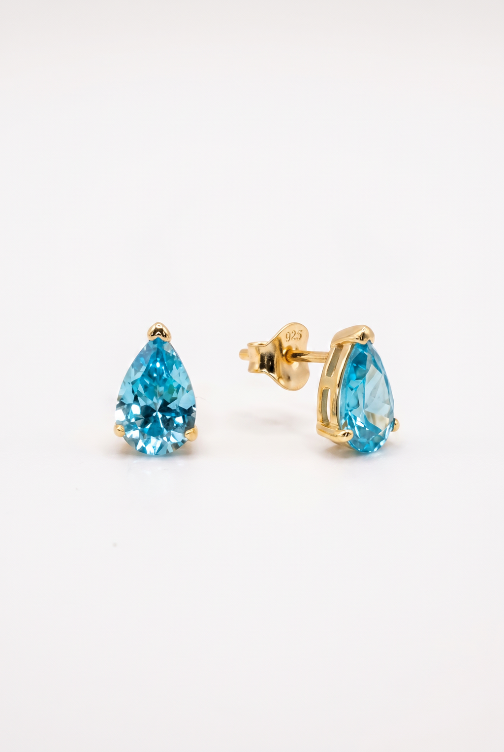 Pair of gold earrings with blue gemstones on a white background
