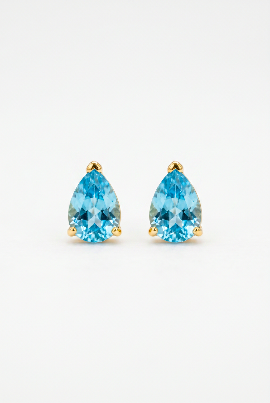 Pair of gold earrings with blue teardrop-shaped gemstones on a light gray background