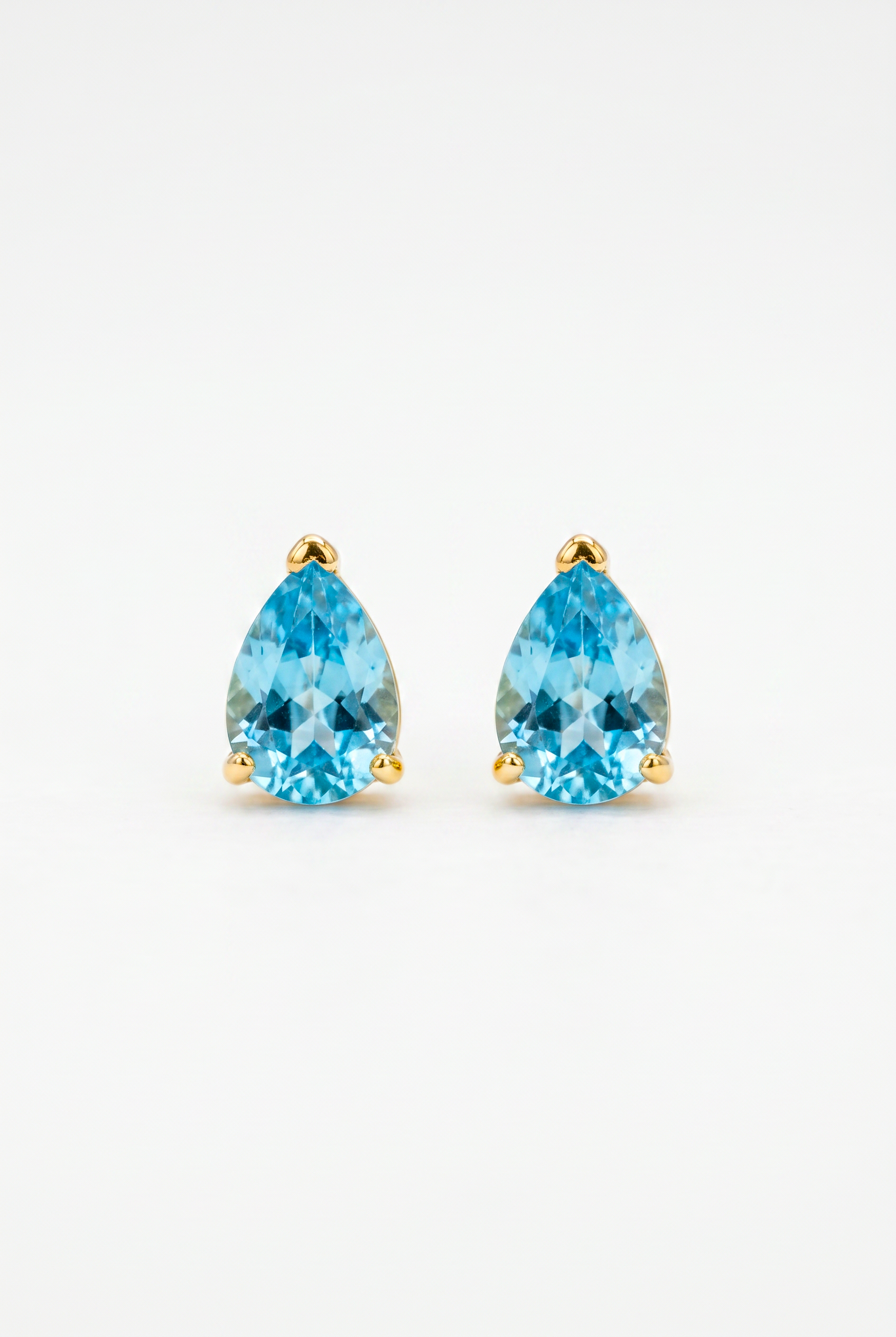Pair of gold earrings with blue teardrop-shaped gemstones on a light gray background